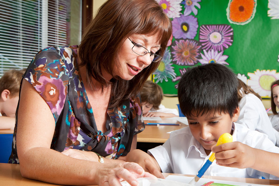 A teacher helping a young student in a classroom.