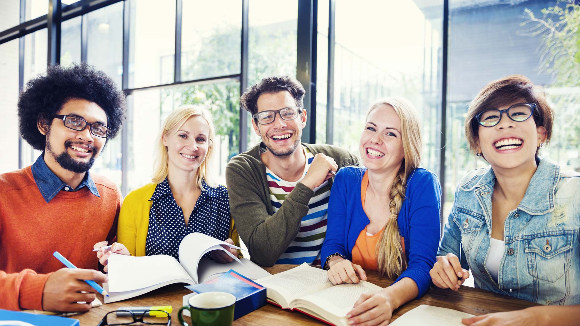 A group of professionals with notebooks and papers on the table in front of them, smiling at the camera.