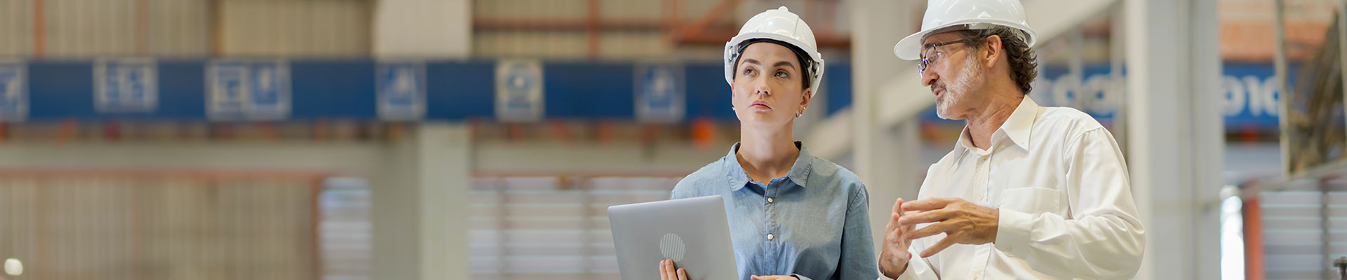Man and women wearing hardhats looking at a clipboard