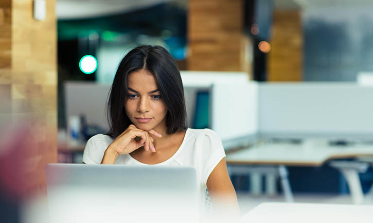 A woman sat at a table working on a laptop