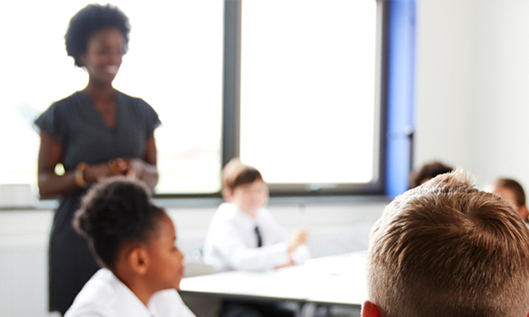 A teacher in front of a window, facing in to pupils at their desks