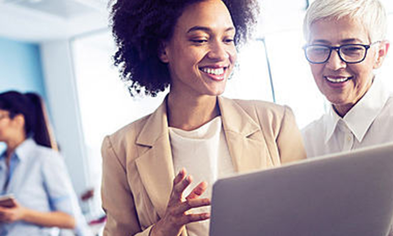 A student talking to a lecturer in front of an open laptop